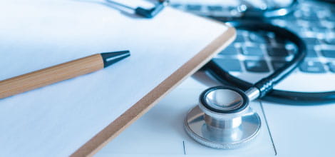 Pen, notepad, stethoscope on laptop